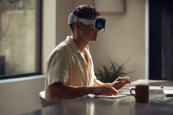 A person wearing Apple Vision Pro sitting at a desk — working.